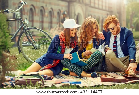 Young beautiful students are sitting and reading near university Royalty-Free Stock Photo #433114477