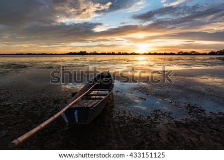 Small fishing boats beached on the riverbank in the park at sunset.
Shows a silhouette of a beautiful sky reflected from the water surface.