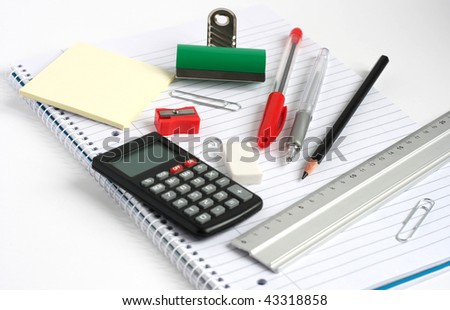 calculator pens pencil ruler bulldog clip on white lined notepad