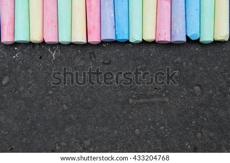 Colorful pastel sidewalk chalk on dark asphalt background. Top view