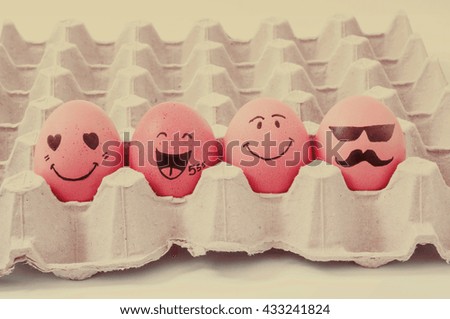 four brown eggs  with faces drawn  arranged in carton
