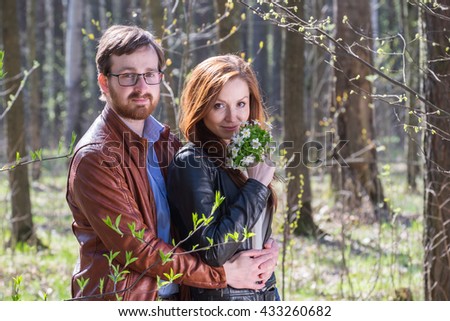 Young lovely couple with bouquet of spring flowers in park