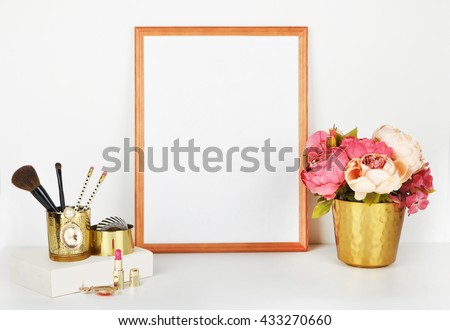 Frame Mock-up for your photo or text . Place your work. Wood frame with gold vase and gold items. Makeup items with gold vase and peonies. White book.