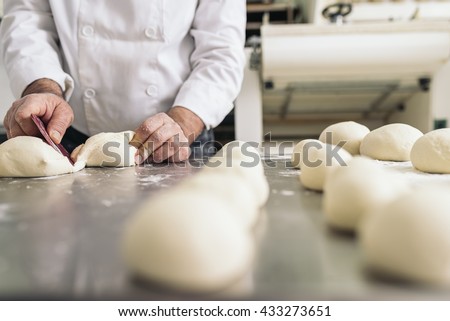 Baker kneading dough in a bakery. Bakery Concept. Royalty-Free Stock Photo #433273651
