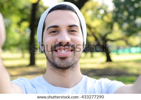 Young latin man taking a selfie in a park. Outdoors.