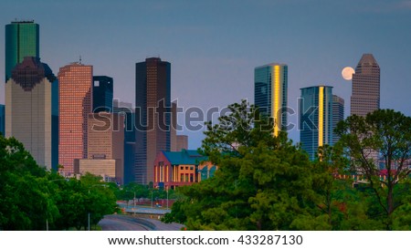 A super moon/full moon rising behind the city of Houston, TX skyline.