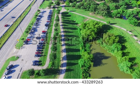 Aerial view of park entrance next to highway in Houston, Texas, US. Also visible is a lake side walking trail surrounded by green trees, warm morning light.Urban recreation, healthy lifestyle.Panorama