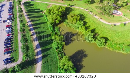 Aerial view of park entrance next to highway in Houston, Texas, US. Also visible is a lake side walking trail surrounded by green trees, warm morning light.Urban recreation, healthy lifestyle.Panorama