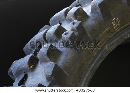 Closeup of rounded knobs on a worn out dirt bike knobby tire isolated on black background.