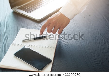 Businessman are holding a pen on the book with computer on Work desk.
