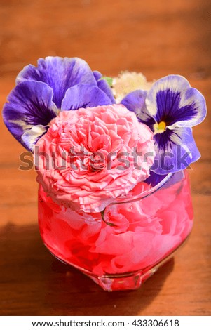 The flower arrangement in color jelly glass ,show colorful clear glass with beautiful flowers .Setting on table or delight event.