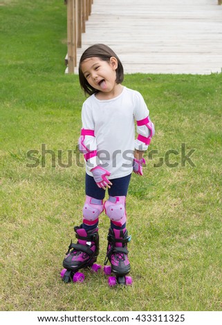 A lovely little girl wearing protection and playing roller skates in park, filtered color tone
