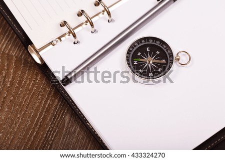 Classic compass on white paper notebook background.
