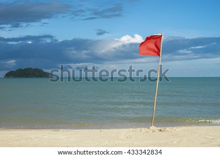 warning sign of a red flag at a beautiful clean beach with a blue sky, cloud and the sea with small green island, natural color picture style
