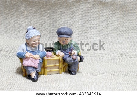lovely grandparent doll siting rocking bamboo chair, grandpa with Smoke pipe in his hand and grandma with Knit and crochet in her hand. -still life 