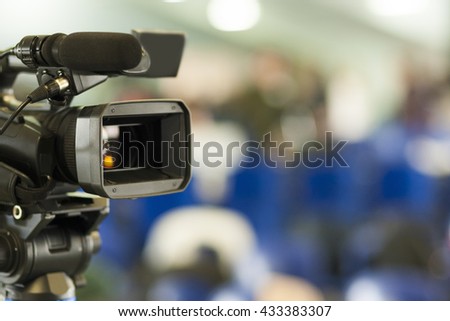 Front View of Professional Videocamera. Positioned Against Blurred Background. Horizontal Image