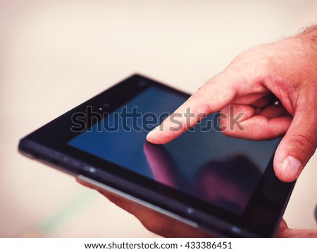 Smart casual man with digital tablet outdoors, close up. Focus on finger. Modern remote work concept.