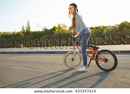 Lovely young woman in a hat riding a bicycle on city background in the sunlight outdoor. Active people