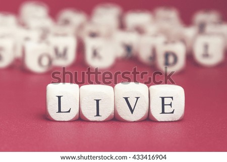 Live word written on wood cube with red background