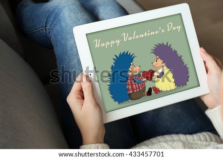 Female hand holding PC tablet with screensaver on home interior background