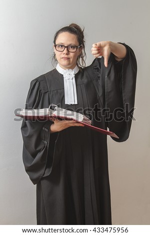 thirty something brunette woman wearing a canadian lawyer toga with a red criminal law book in hand with her thumb down