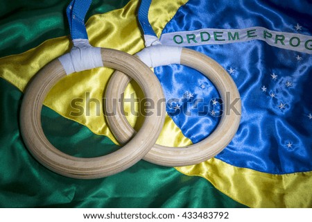 Gymnast rings resting on shiny Brazilian flag background