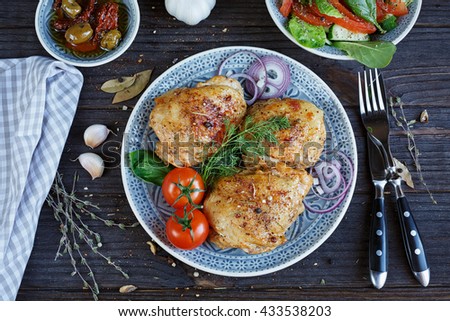 Roasted chicken and vegetables on dark wooden background