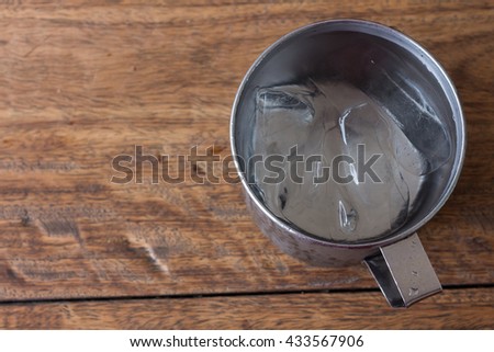 Water in a glass with ice placed on wooden table