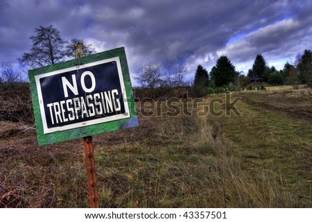 NO TRESPASSING sign in front grass rural country driveway field