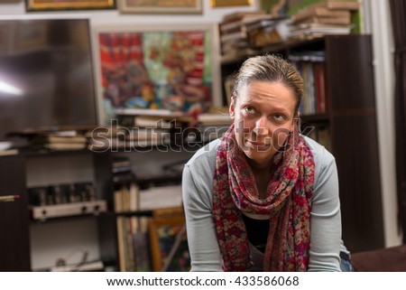 Thoughtful female painter sitting  in a studioor gallery and looking at pictures
