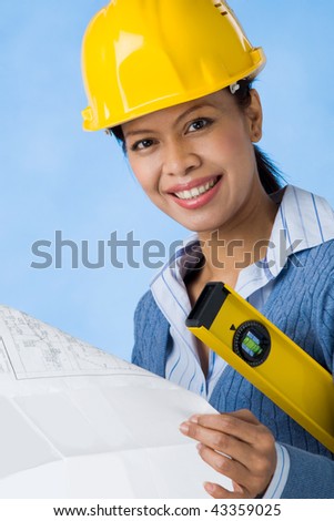 Portrait of pretty female with blueprints in hands and helmet on head smiling