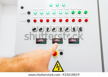 Hand is showing on electrical control panel which contains a digital display for temperature check