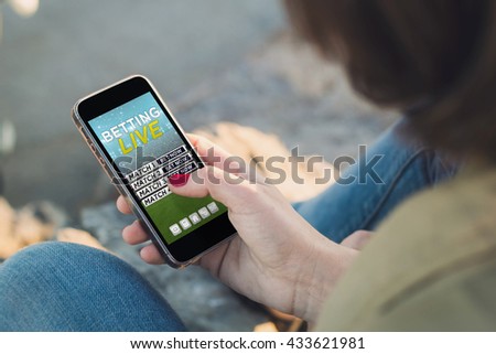 woman holding a smartphone and touching the screen with betting online website. All screen graphics are made up.