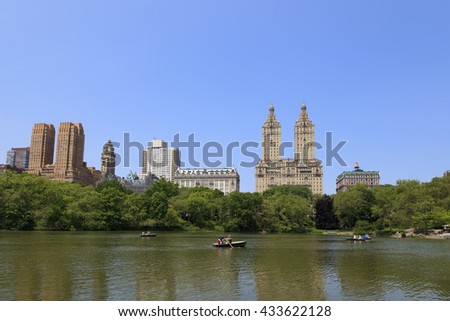 New York City Central Park with Manhattan skyline skyscrapers and blue sky with boat in lake.