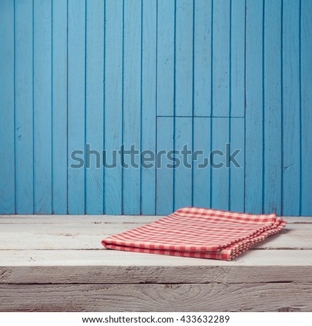 Empty wooden white table with checked tablecloth over blue wooden wall