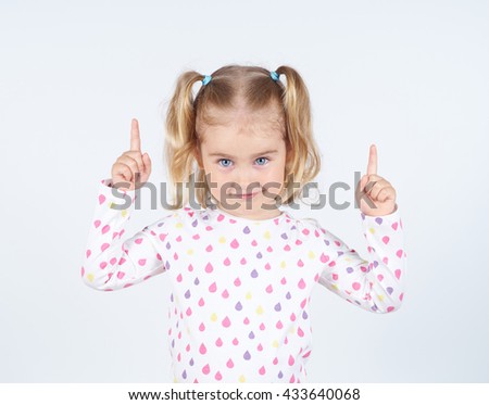 little girl wearing  pointing by forefinger to somewhere up isolated      