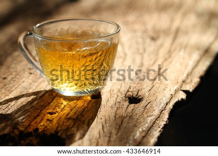 Low key picture, shilouette of tea cup on a wood background. Selective focus
