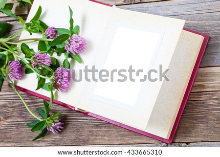 album with open pages and blossom clover on aged boards of antique table. mock up