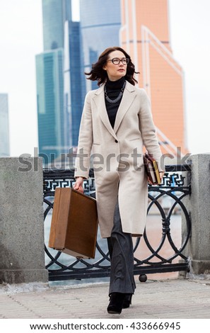 designer businesswoman. beautiful dark-haired middle-aged woman in a bright coat and wooden briefcase in hand goes on the presentation of the project