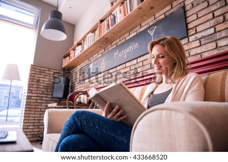 Blond woman with newspaper in cafe drinking coffee