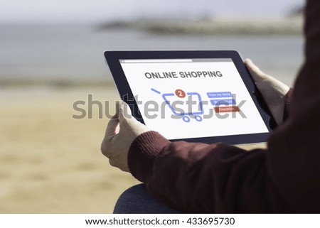 Man sitting on the beach and using his digital tablet to shop online