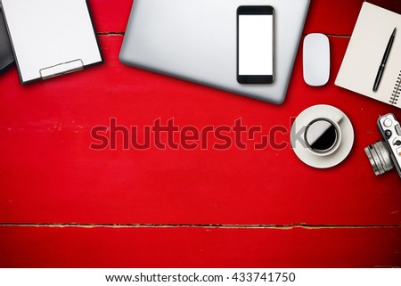 Top view of laptop and smart phone empty white screen material office desktop on red wooden desk.