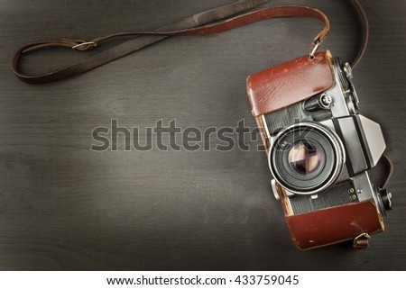 Old camera in a leather case on a black wooden background. The camera of the past. Advertising for the sale of the camera. For roll film camera. Equipment artistic photographer.