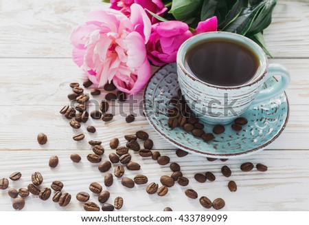 Cup of coffee, coffee beans and bouquet of peonies on rustic wooden background