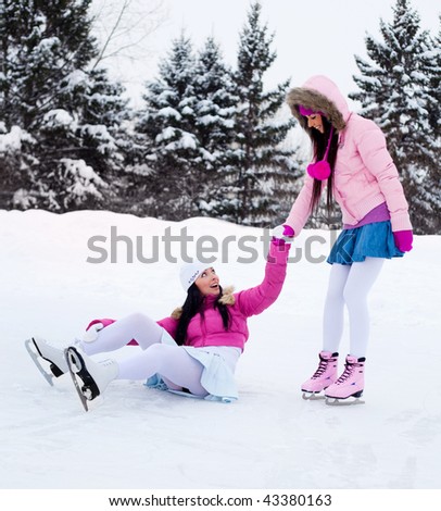 two beautiful girls wearing warm winter clothes ice skating