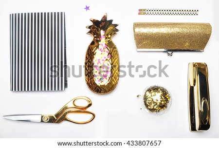 Flat lay. Accessories on the table, woman desk top. View top table, background mock up. Gold stationery,gold pineapple, handbag, notebook, pencil.Black and white