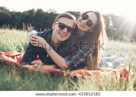 Cheerful young man and girl lie outdoors in the sunlight