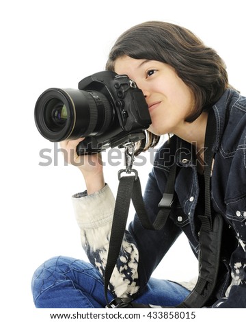 A young teen girl sitting in the corner of the image, happily taking pictures with a pro camera.  On a white background.