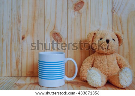 A coffee cup with teddy bear and wooden background. vintage style.