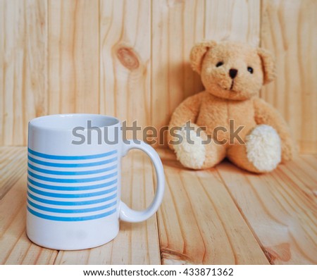 A coffee cup with teddy bear and wooden background. vintage style.